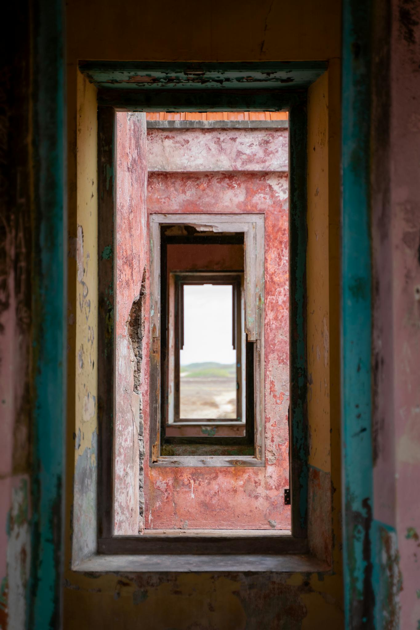 Rustic view through a series of colorful, weathered doorways in an abandoned building, Curaçao.