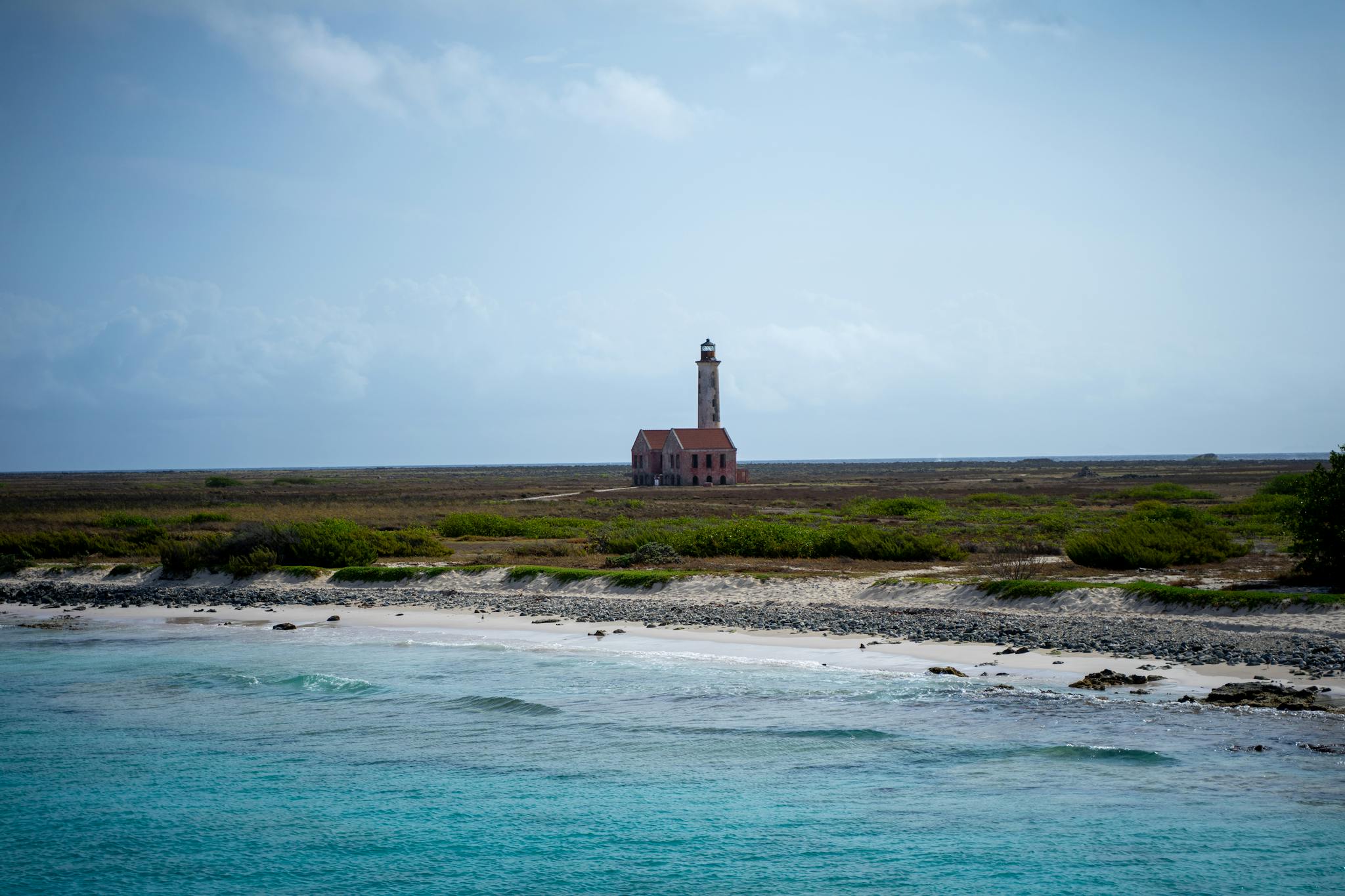 Scenic coastal landscape featuring the abandoned lighthouse of Klein Curaçao under a bright sky.