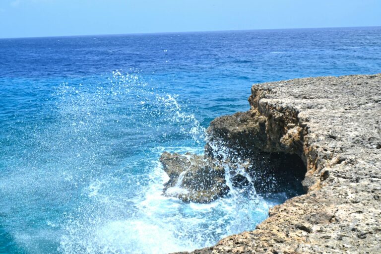 Vibrant ocean waves splashing against the rocky shoreline of Curaçao. A perfect tropical seascape for travel inspiration.